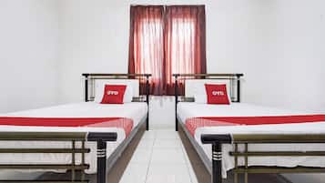 Une chambre avec deux lits, chacun recouvert d’une couvre-lit rouge et blanche, et une fenêtre avec des rideaux rouges.