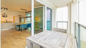 Et moderne køkken med spiseplads, et stort vindue og en skydedør, der fører ud til en balkon.