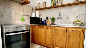 Una cocina con estufa, armarios de madera, microondas y fregadero.