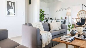 A modern living room with a grey sofa, a wooden coffee table, and a hanging chair. - Kalafatis Stay with Private Pool (Kalafati)