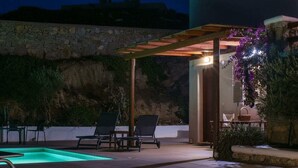 An outdoor pool area with lounge chairs, a pergola, and a stone wall. - Ano Mera Villa with Private Pool (ano mera)