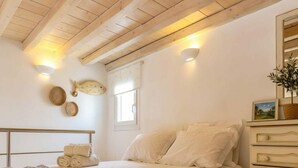 A bedroom with a bed, bedside tables, a window, and wall decor. - Ano Mera Villa with Private Pool (ano mera)