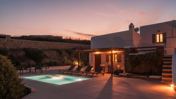 A modern villa with a swimming pool, lounge chairs, and a stone wall. - Ano Mera Villa with Private Pool (ano mera)