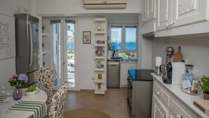 Una cocina compacta con refrigerador, cafetera y vista al mar.