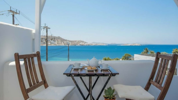Un balcón con una mesa dispuesta para dos, con vistas a la costa.
