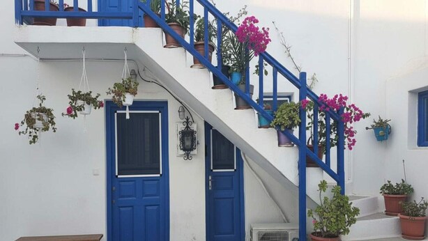 Un bâtiment blanc avec des portes bleues et un escalier.