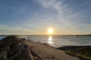 A coastal scene with a sunset, a sandy beach, and a rocky breakwater. - The Sea Homestay Phan Thiet (Phan Thiet)