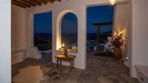 Un interior acogedor con suelo de piedra, una mesa de madera y vistas al mar a través de amplios ventanales.