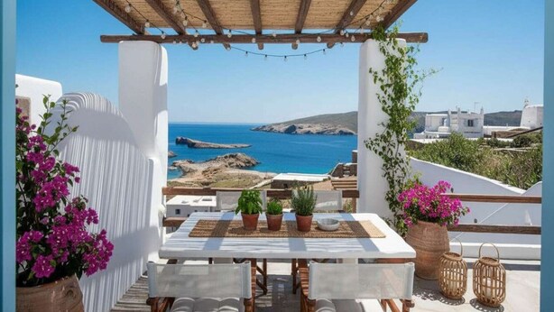 Un espacio exterior con mesas y sillas, plantas en macetas y vista al mar.