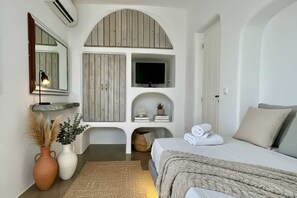 Ein Schlafzimmer mit einem Bett, einem Fernseher, einem Spiegel und einem Regal mit Dekoration.