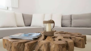 Una mesa redonda de madera con un candelabro, revistas y un sofá con cojines al fondo.