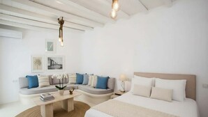 Un dormitorio moderno y minimalista con cama, sofá curvo, mesa de centro y lámpara colgante.