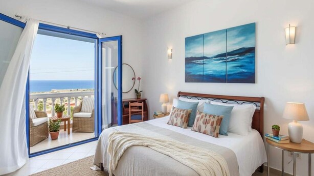 A bedroom with a bed, a view of the sea, a painting, and a balcony with wicker furniture. - Pool Villa Overlooking the Sea (kalathos)