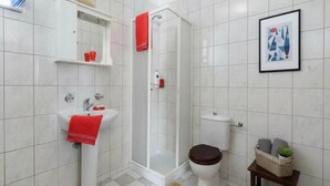 A bathroom with a shower, toilet, sink, and a framed picture on the wall. - Pool Villa Overlooking the Sea (kalathos)