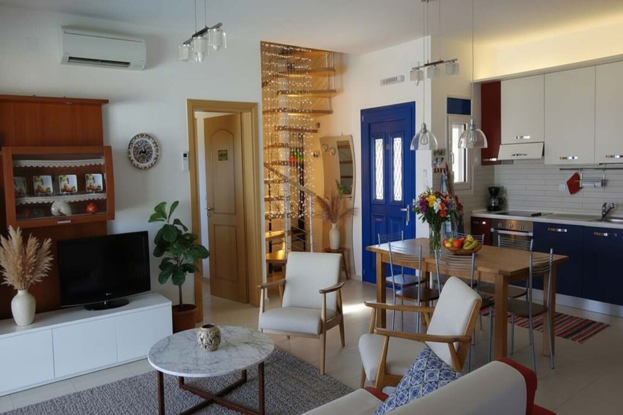 Una sala de estar moderna con televisor, asientos, una zona de comedor y una cocina.