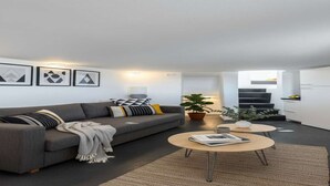 A modern living room with a grey sofa, a round coffee table, and a staircase leading to an upper level. - Dionysos Wine Stay, Mountain Views (Emporeio)