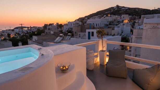 A rooftop terrace with a hot tub, lounge chairs, and a view of a coastal town at sunset. - Dionysos Wine Stay, Mountain Views (Emporeio)