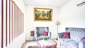 A living room with a sofa, armchair, and a table with a red and white tablecloth.