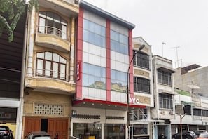 Un edificio de varios pisos con un llamativo letrero 'OY', grandes ventanales y un balcón en el segundo piso.