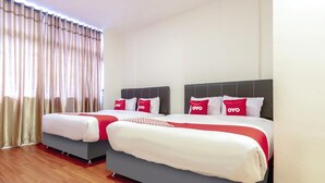 A hotel room with two beds, each with a grey base and white bedding, red pillows with 'OYO' branding, and a wooden floor. - Family Luxury Suite W/Free WiFi and Parking (Medan)
