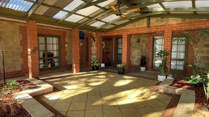 A covered patio area with brick walls, potted plants, and a ceiling fan. - Beach and Winery getaway. The perfect base for a family holiday. Pet friendly (Seaford)
