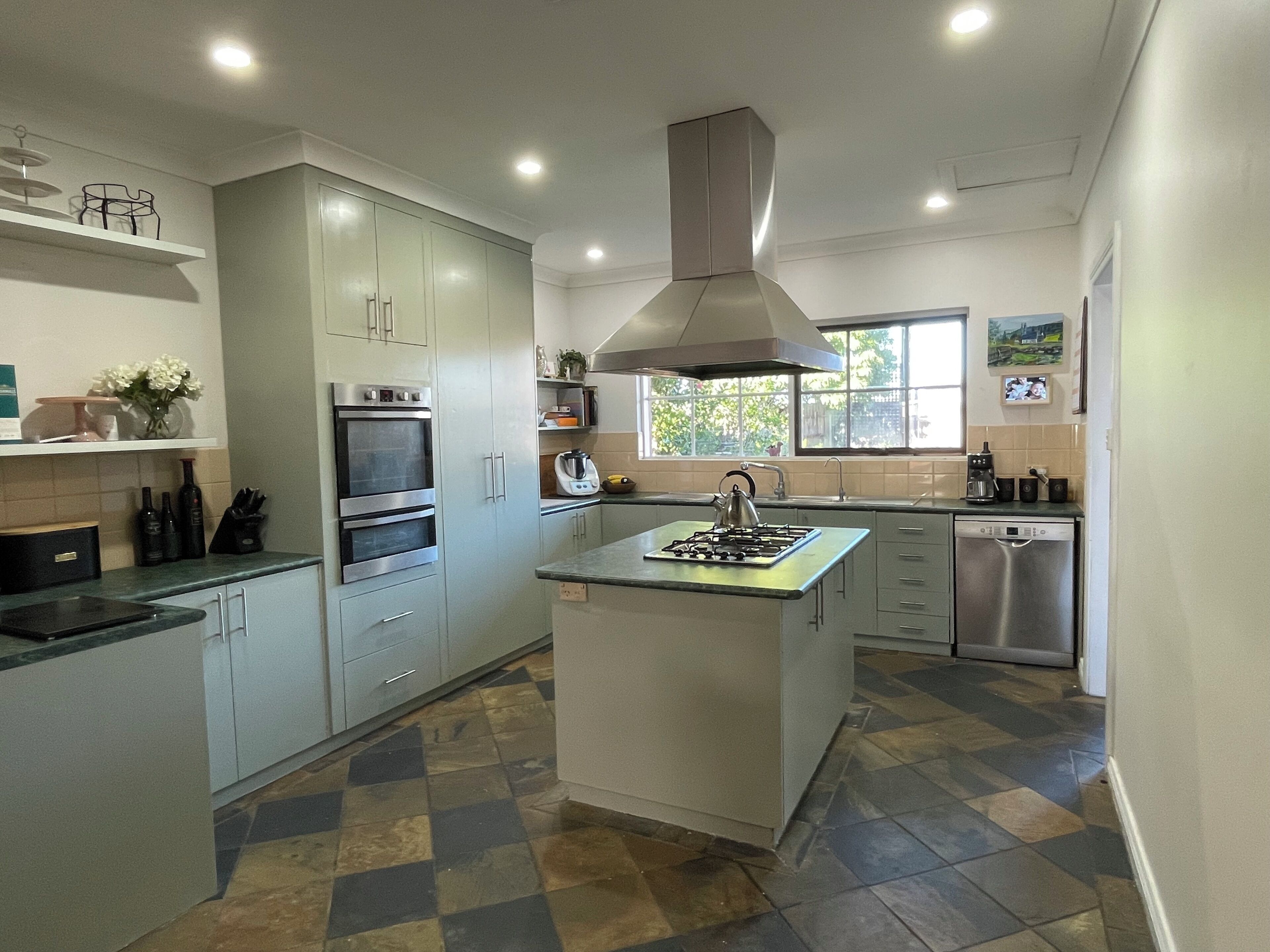 A modern kitchen with a central island, built-in oven, and stainless steel appliances.