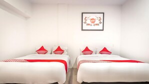 Ein Hotelzimmer mit zwei Betten, jeweils mit rot-weiß gestreifter Bettwäsche, einem gerahmten Bild an der Wand und einem Holzboden.