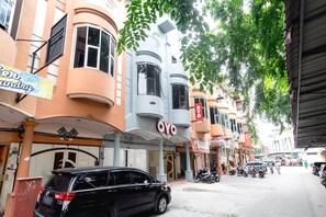 A street with buildings, a black SUV parked, and a sign for 'OYO'.