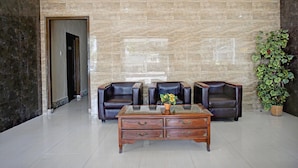 A lobby with a marble wall, leather chairs, a wooden coffee table, and a potted plant. - Luxury Twin Comfort Stay W/ Free Parking and Pool (Medan)