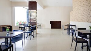 Un comedor amplio con varias mesas y sillas, un ventanal con vistas y un panel decorativo en la pared.