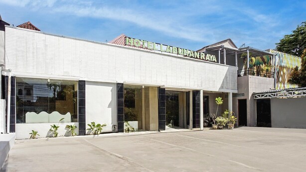 Un hotel moderno con un cartel llamativo, ventanas amplias y una zona de acceso cubierta.