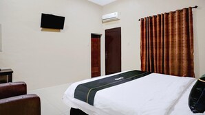 Habitación de hotel con cama, televisión montada en la pared, aire acondicionado y dos puertas.