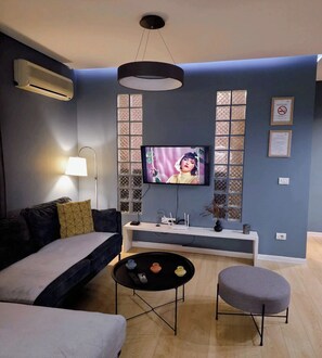 Un salon comprenant un canapé, une table basse, un téléviseur et un panneau décoratif mural.