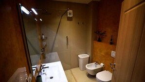 A modern bathroom with a glass shower enclosure, a white sink, a bidet, and a toilet. - Arkle Apartment 9 (Tirana)