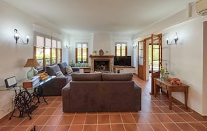 A living room with a fireplace, sofas, a television, and a dining area with a table and chairs. - ES FIGUERAL SON RIBAS (Alaro)