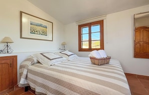 A bedroom with a bed, a window, a lamp, and a framed picture on the wall. - ES FIGUERAL SON RIBAS (Alaro)