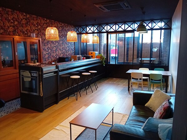 A modern bar area with a counter, stools, and a seating area with a couch and chairs.