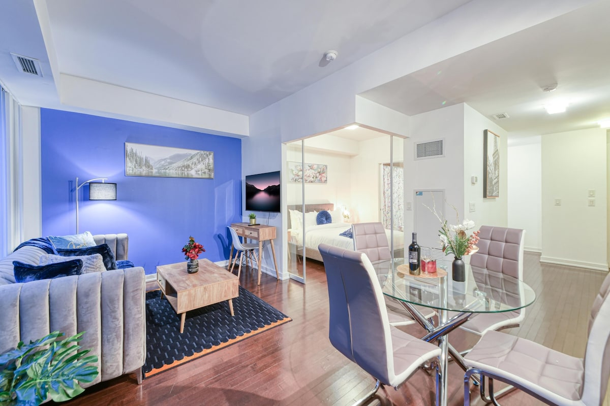A modern living room with a blue accent wall, a sofa, a glass coffee table, and a TV.