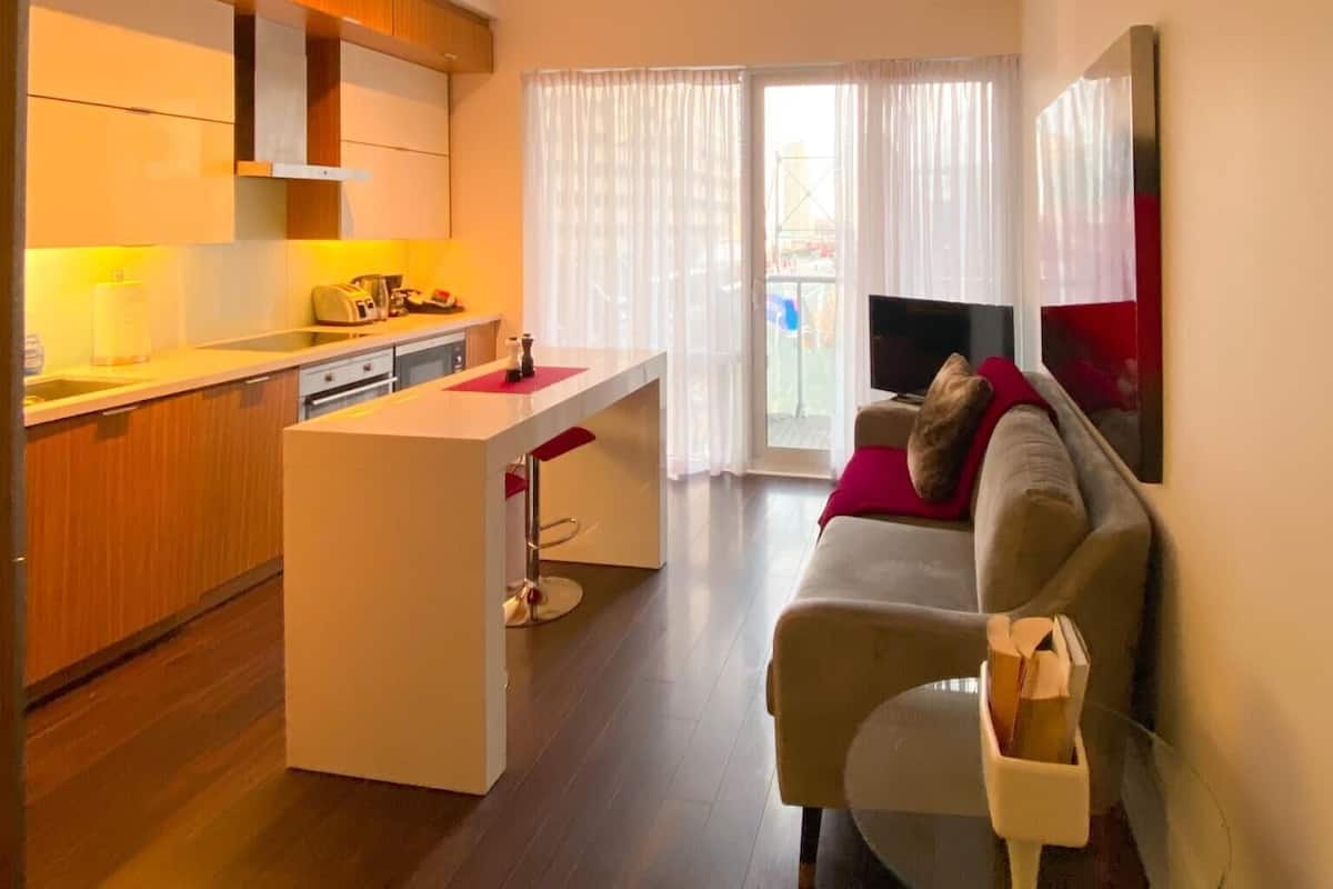 A modern kitchen with a central island, a dining area with a sofa, and a TV on a stand.