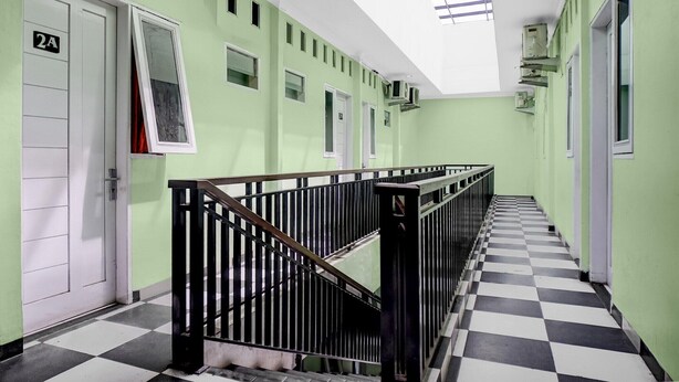 Ein Korridor mit Schachbrettfußboden, grünen Wänden und einer Treppe mit schwarzen Geländern.
