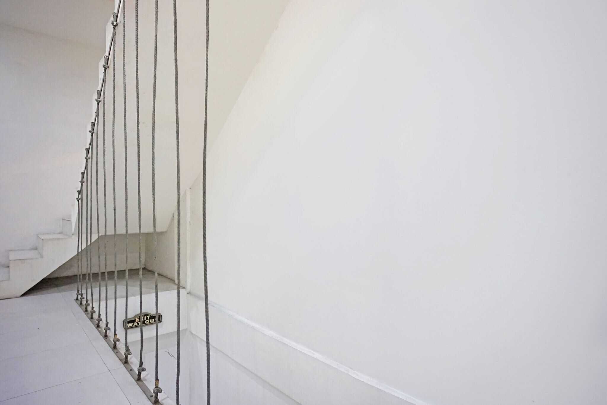 A staircase with a handrail, a sign indicating an exit, and a white wall.