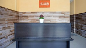 A reception desk with a sign reading 'Kool Kost' and a potted plant.
