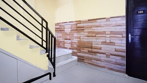 A staircase with a black railing, a stone wall, and a door with the number 105.