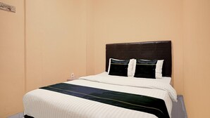 A single bed with a dark headboard, white bedding, and a dark-colored throw blanket.