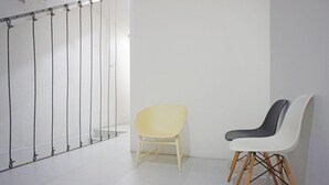 Une pièce avec un sol blanc, une chaise jaune et une chaise blanche avec des pieds en bois.