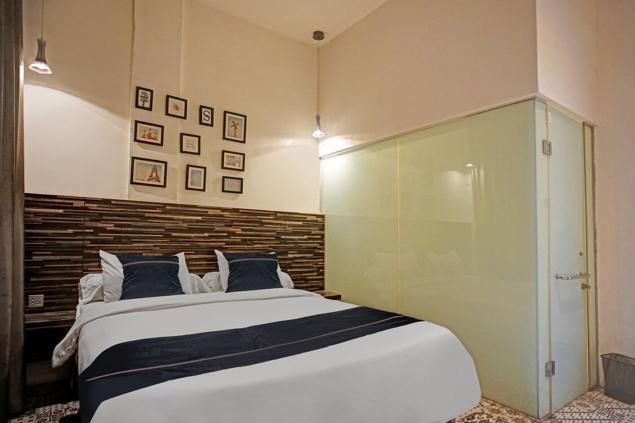 A bedroom with a bed, a wooden headboard, a wardrobe, and framed pictures on the wall.
