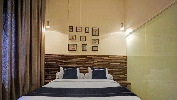 Une chambre d’hôtel avec un lit, une tête de lit ornée d’un motif et des tableaux encadrés accrochés au mur.