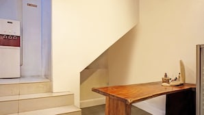 Un escalier menant à un palier où se trouvent une table en bois et un distributeur d’eau.