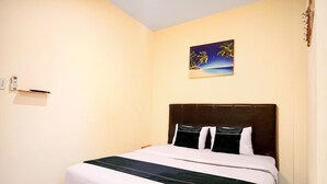 Une chambre d’hôtel avec un lit, une table de chevet, un tableau représentant une scène de plage et un téléphone fixé au mur.