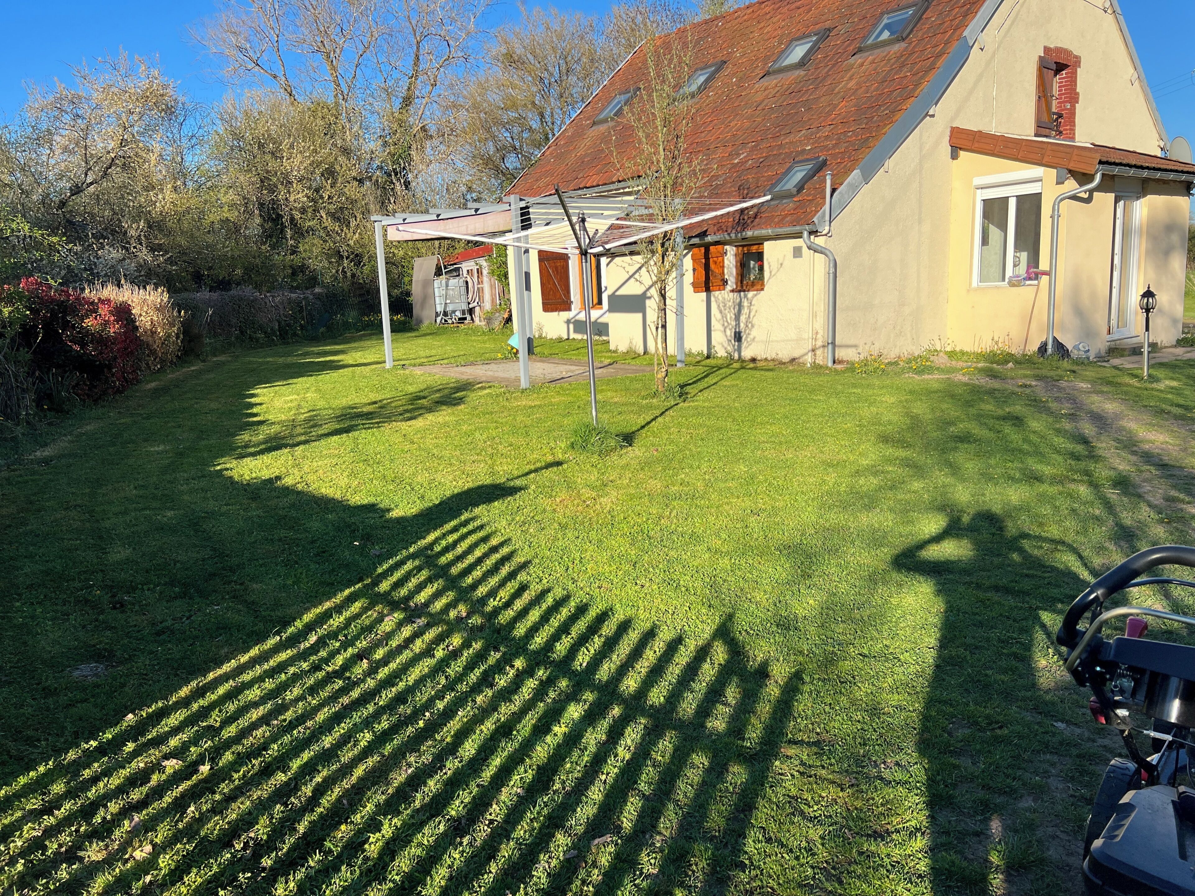 Une maison avec un toit en pente, un patio couvert et une pelouse bien entretenue.